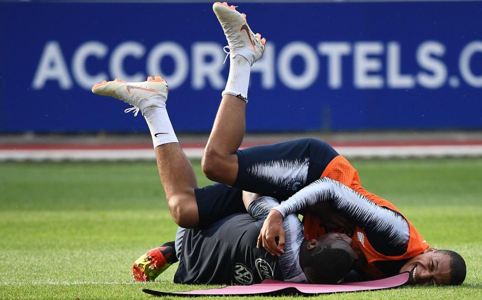  Mbappe and Paul Pogba wrestle on the ground with smiles on their faces