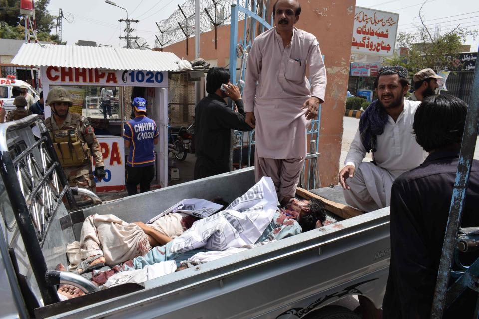 Locals help to transport the bodies of blast victims at a hospital after a suicide attack on election day