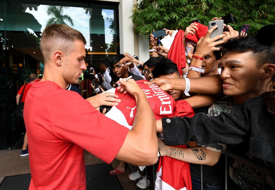 Ramsey signs the shirts of fans in Singapore - but is yet to sign the new contract on offer