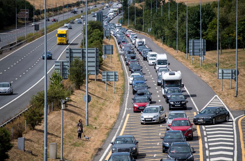  A holidaymaker walks her dog amongst stationary traffic as cars queue for the Eurotunnel