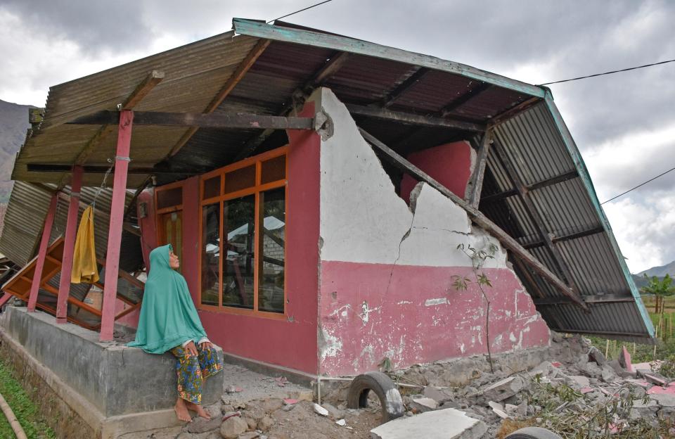  A villager sits at her damaged house after the earthquake that hit the tourist destination next to Balli