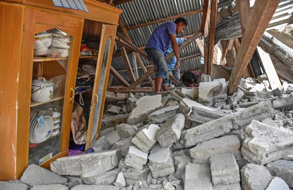  A villager walks through the ruins of a collapsed house during a search for the equipment of Malaysian tourists who died during the earthquake