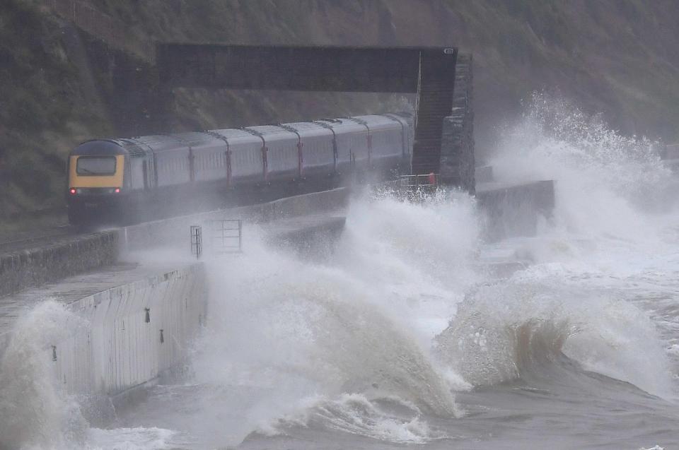  Large waves in strong winds hit the sea wall as a train passes at Dawlish in South West England this morning