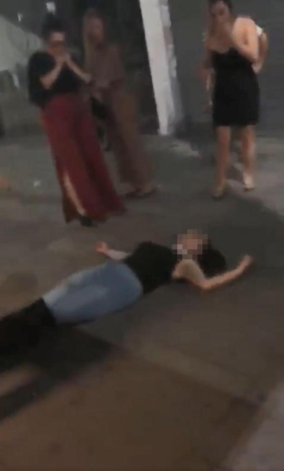  The girl lays spark out on the street as her stunned mates stand around her