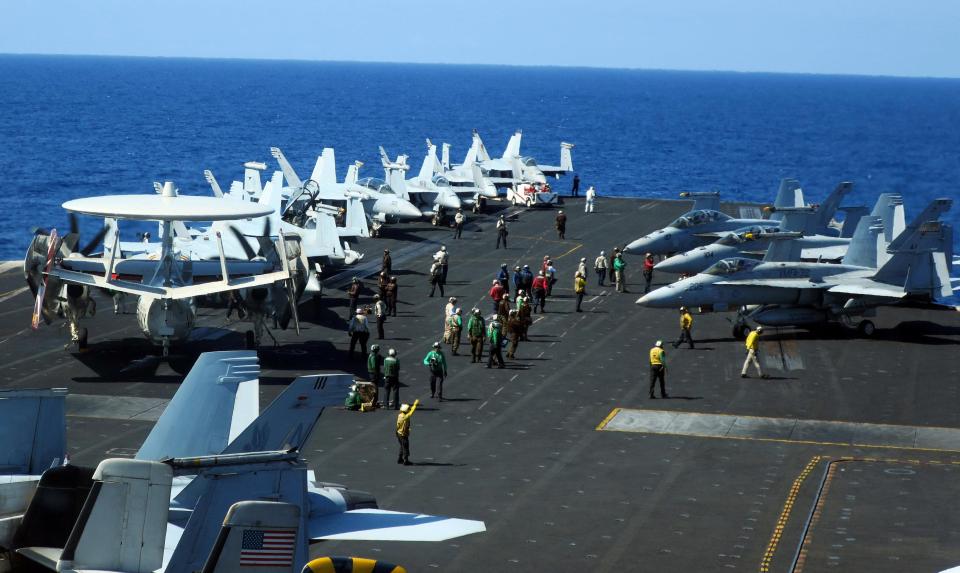  Carrier air crew converge at the flight deck of USS Theodore Roosevelt to guide operating aircraft while transiting the South China Sea