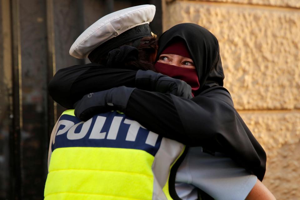  A niqab wearer weeps as she is embraced by a police officer during the demonstrations