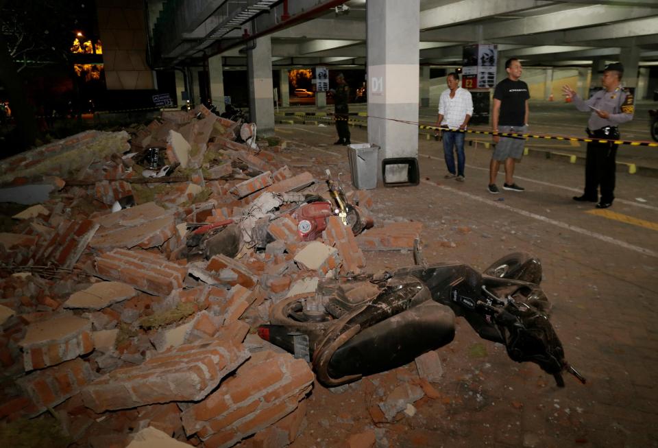  A policeman examines debris that fell and crushed parked motorbikes following a strong earthquake on nearby Lombok island, at a shopping centre in Kuta, Bali