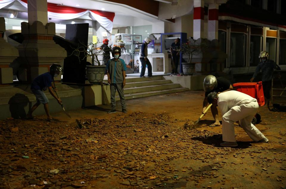  People clean up debris following a strong earthquake on nearby Lombok island, in Denpasar, Bali