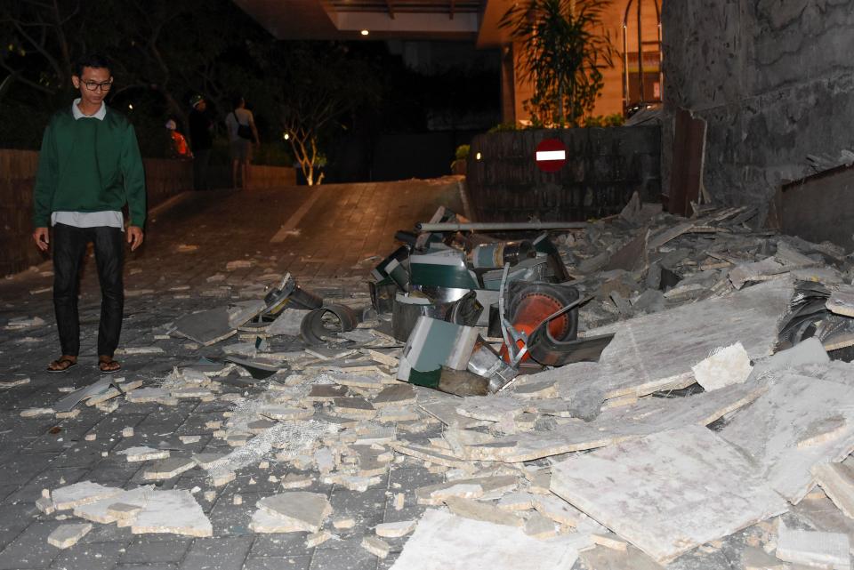  A man walks past debris which fell from a signboard outside the Santika hotel