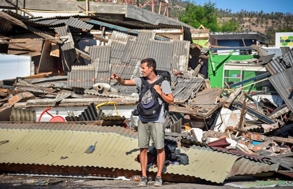  A foreign tourists stands next to some destroyed buildings in Pemenang, north Lombok