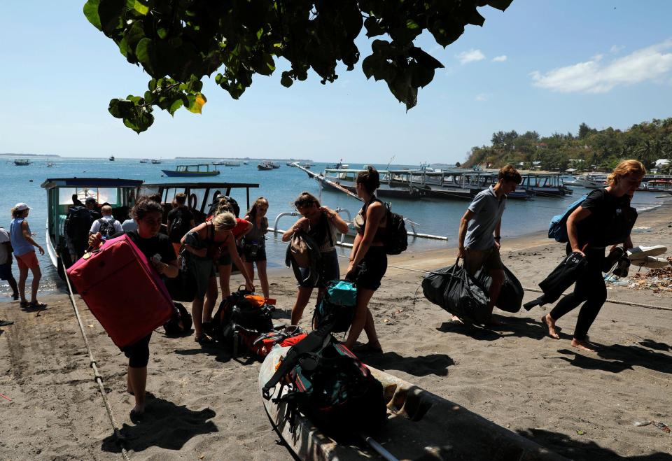  Foreign tourists carry their belongings on the beach as they leave Gili Trawangan island