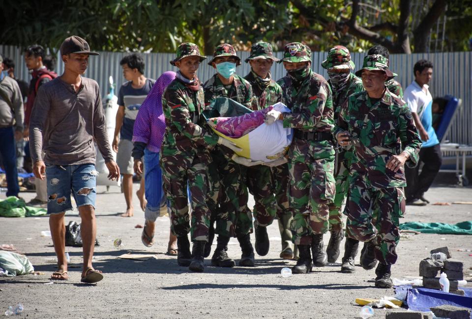  Indonesian soldiers carry the body of an earthquake victim to an ambulance at North Lombok District General Hospital