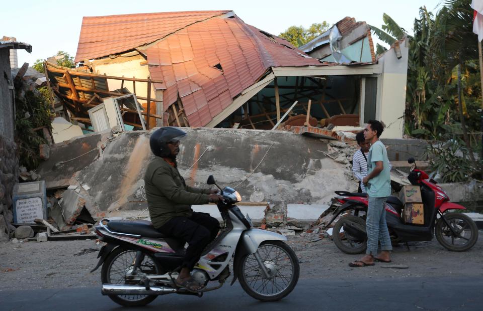  A man on a bike rides past the ruins of houses in North Lombok just east of Bali