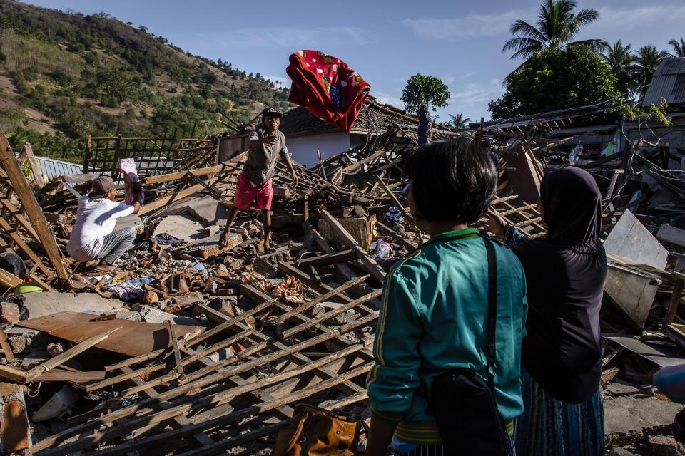 People search for their belongings at collapsed houses following earthquake in Tanjung