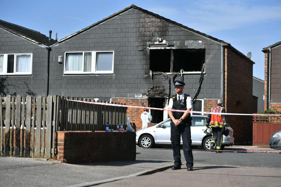 An officer stands outside the home as the arson investigation begins