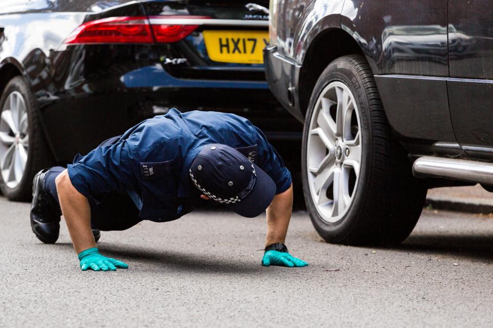  A police officer examines under a car as part of their investigations