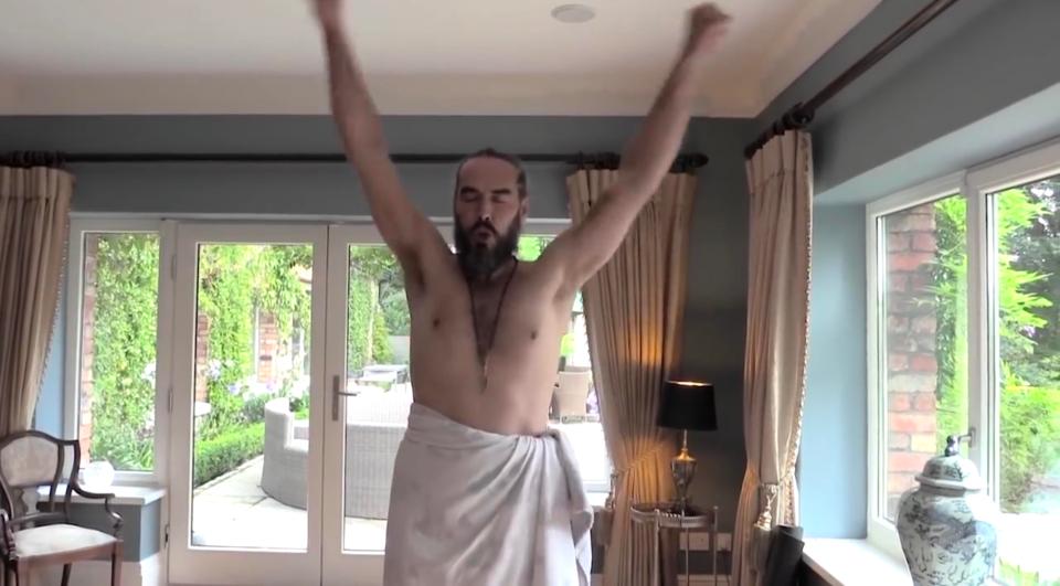  Russell Brand wears just a bed sheet around his waist as he demonstrates yoga moves