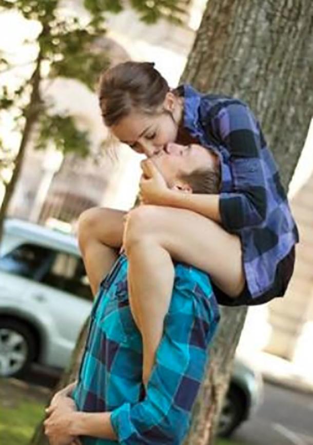  This groom bends his head back to kiss his bride-to-be as she perches on his shoulders