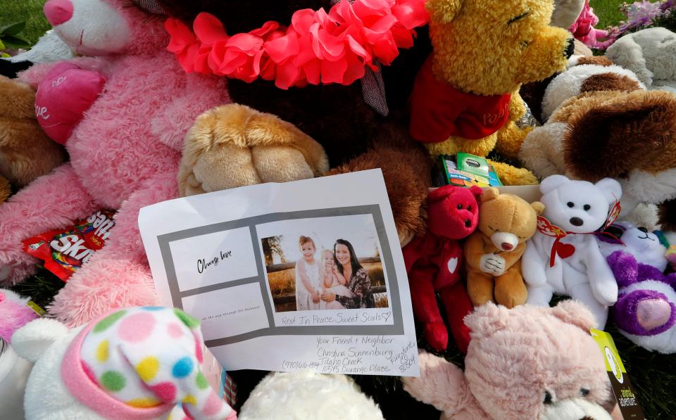  The memorial outside the Watts' family home includes flowers, stuffed animals, and cards