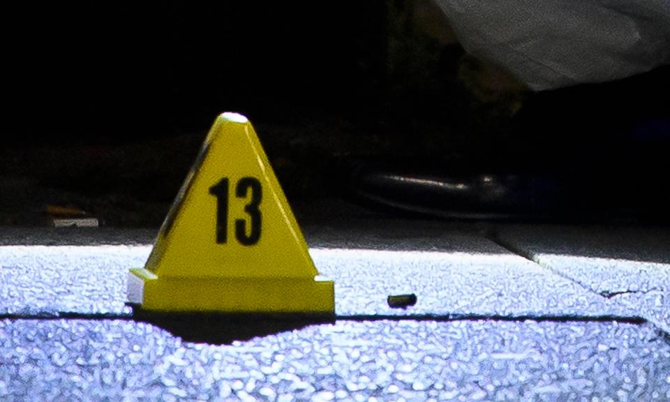  Police forensics examines a bullet casing at the scene of a shooting