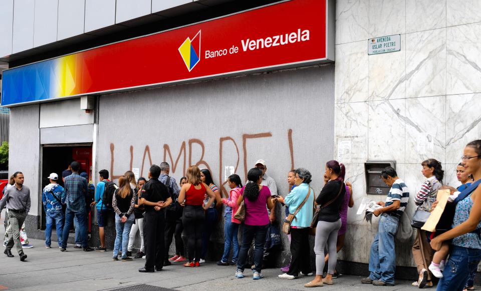  As crowds queue for cash from the bank, the graffiti on the wall translates as 'HUNGRY!'