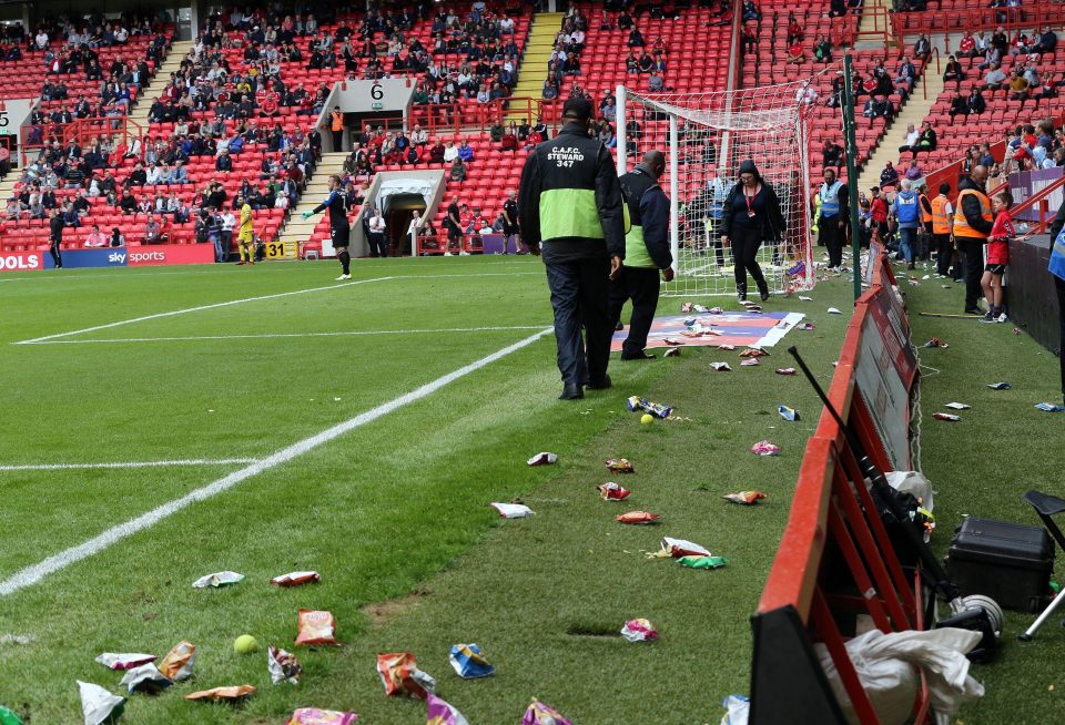  Stewards attempt to clear the crisp packets away from the field