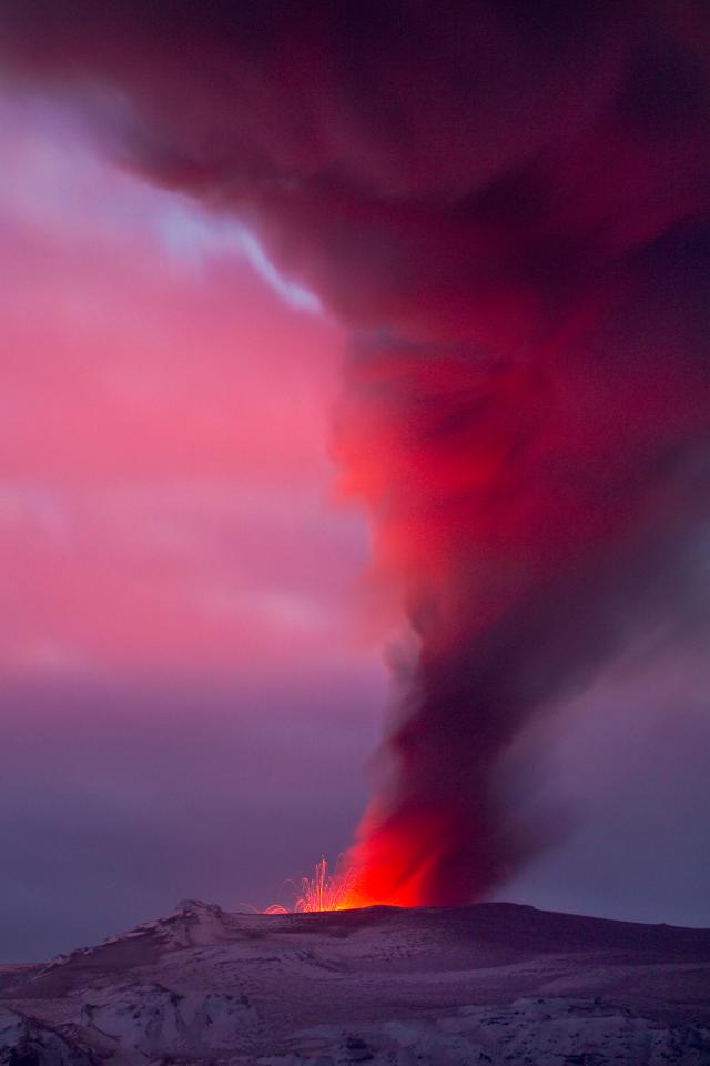  Eyjafjallajokull volcanic eruption showing ash plume illuminated by lava in Iceland, April 2010