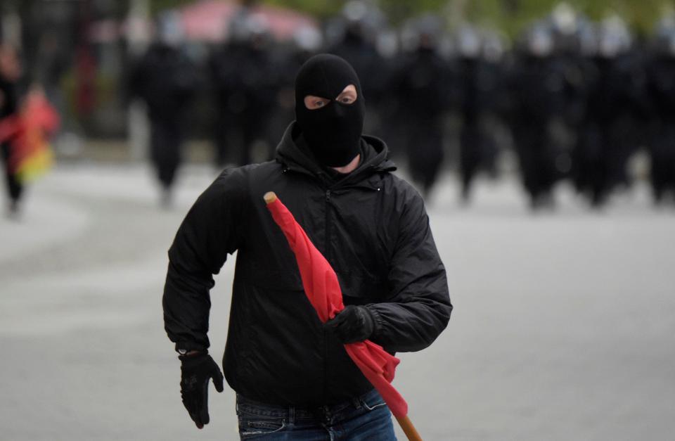  A masked leftist demonstrator flees approaching police who try to separate leftist and nationalist demonstrators