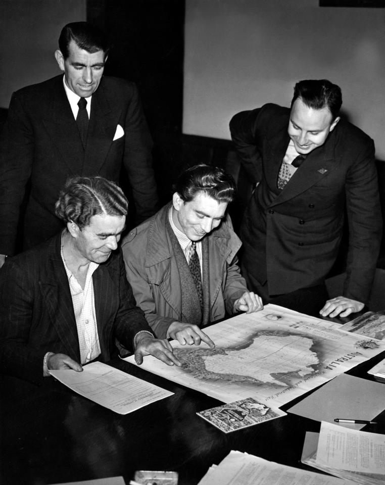  Two men inspecting a map of Australia with immigration officials in 1952