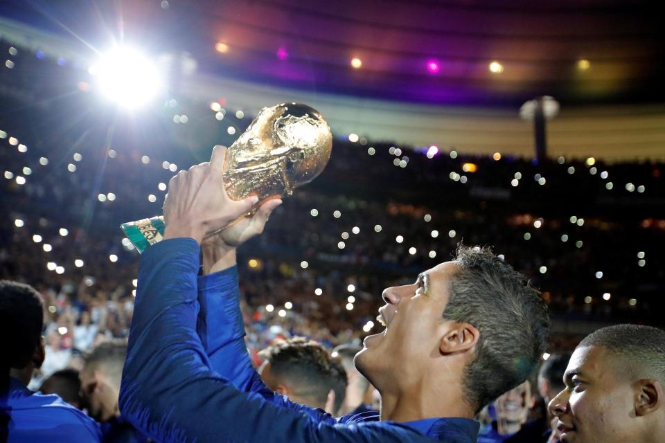 Rafael Varane holds the World Cup trophy aloft to thousands in the stadium