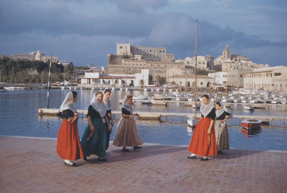  Women wear traditional Spanish dress down by the harbour in Majorca in the 1960s