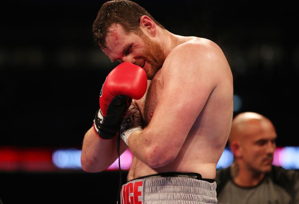  Price holds his right bicep as he was forced to quit on his stool at Wembley