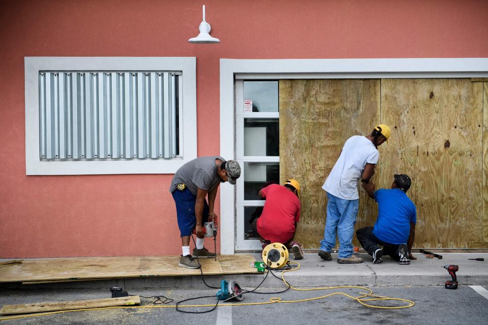 Workers of a local business in Panama City board the windows of the store front