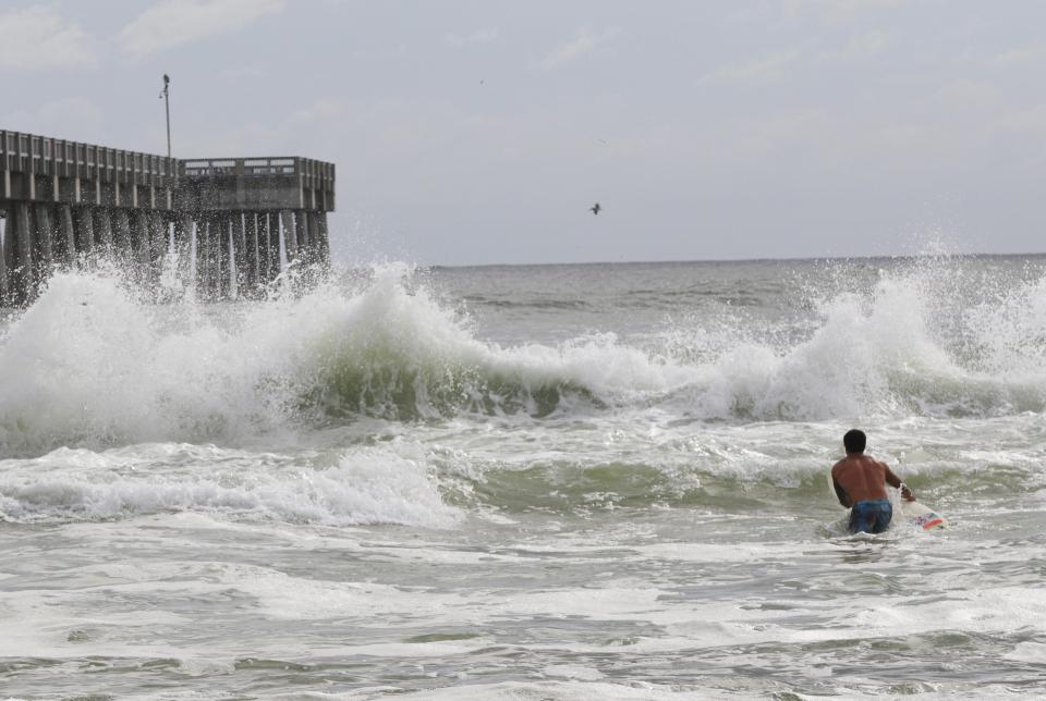 A surfer sits in the as Hurricane Michael approaches Panama City