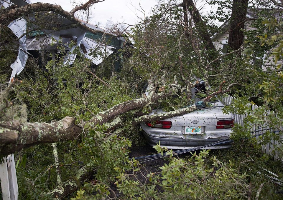  A tree lays on a home and car after the storm battered Panama City, Florida