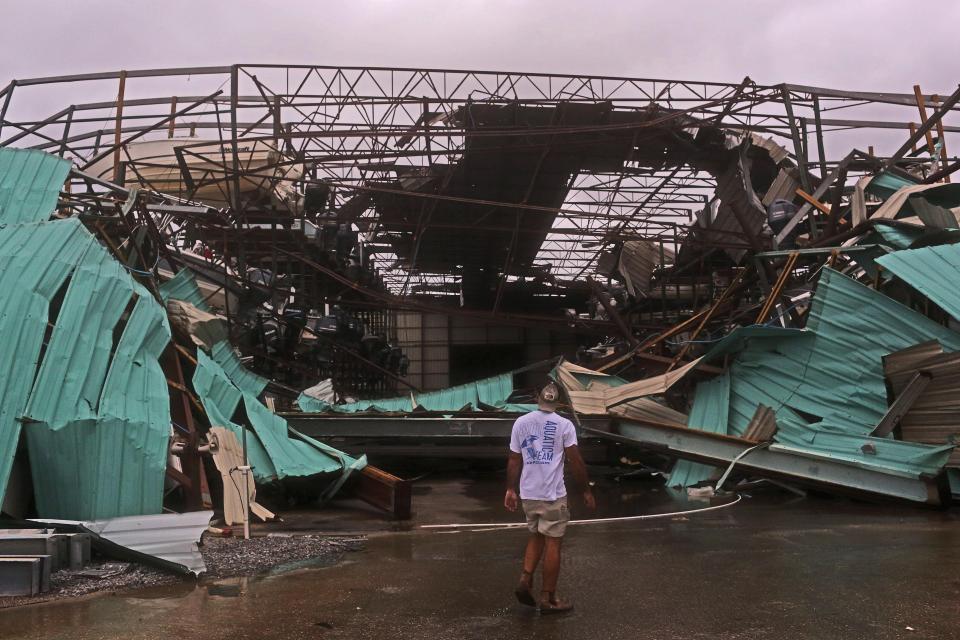  A local inspects the wreckage of a collapsed boat housing station