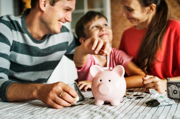 a family putting money into a pink piggy bank