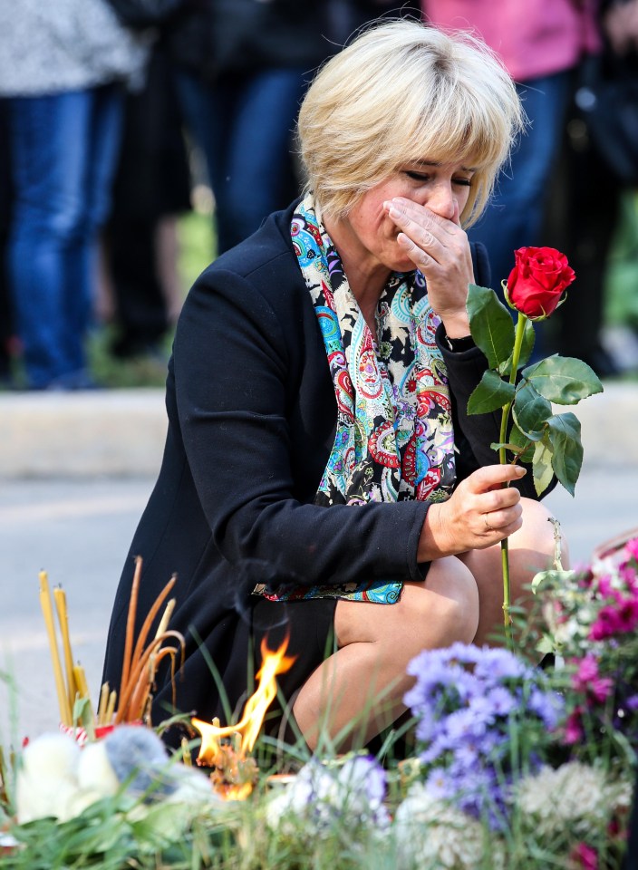 A distraught woman kneels down and lays a single rose