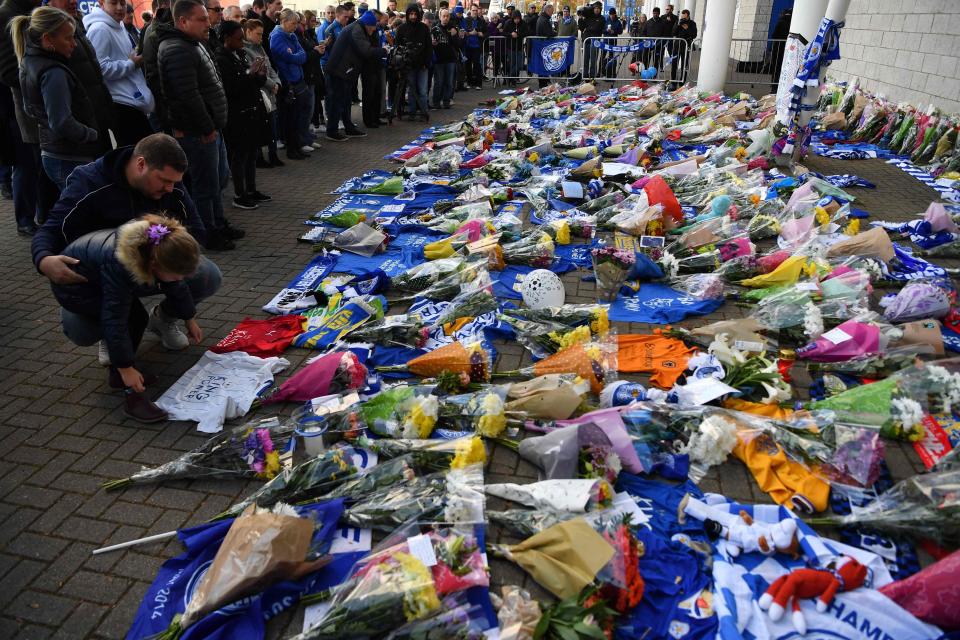  A man and child lay a shirt at the stadium tributes this morning