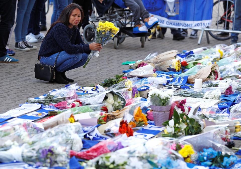  A woman pauses and appears emotional as she adds flowers to a growing pile of tributes outside Leicester City Football Club's King Power Stadium