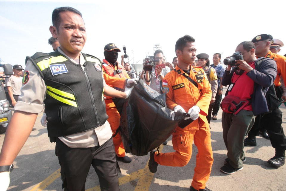 Rescue workers carry a body in a bag at at Tanjung Priok Harbour in Jakarta