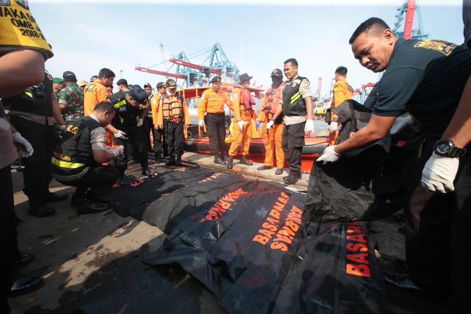  Emergency workers arrange body bags at the harbour as the search for the wreckage continues