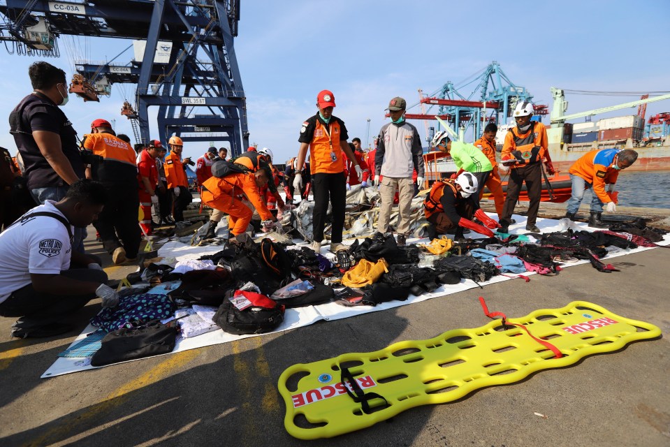 Members of a rescue team collect personal items and wreckage at the port in northern Jakarta