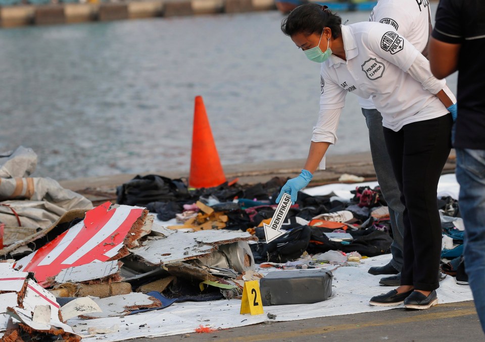 A police officer inspects debris recovered from the area where the passenger jet crashed at Tanjung Priok Port in Jakarta