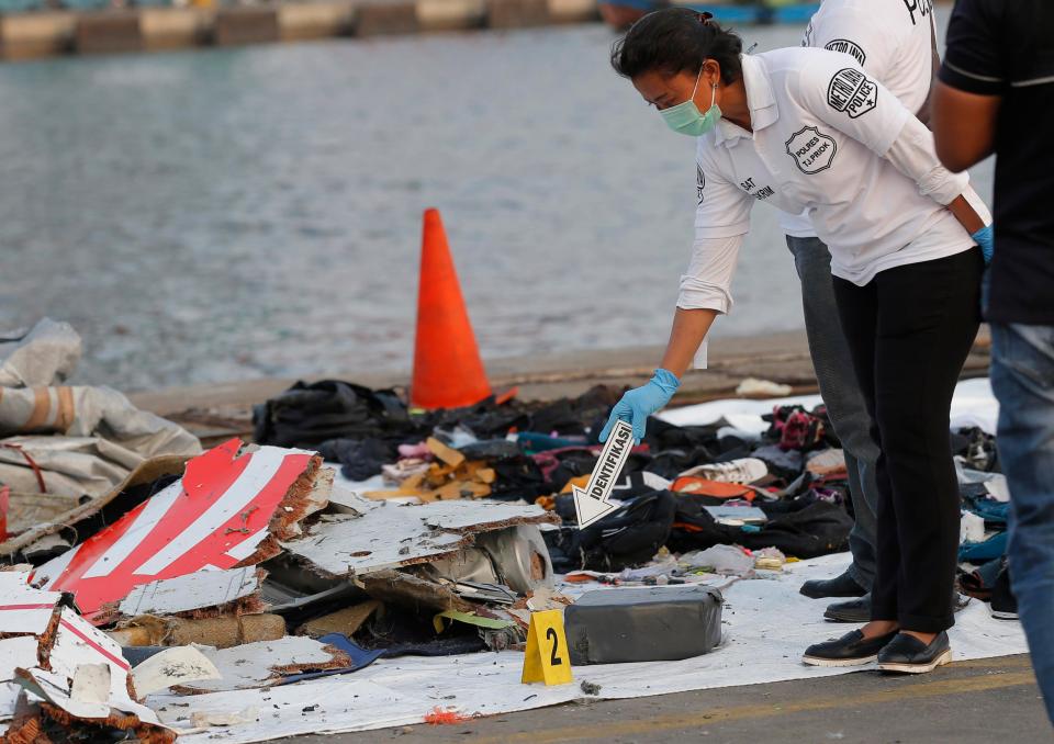  A police officer inspects debris recovered from the area where the passenger jet crashed at Tanjung Priok Port in Jakarta