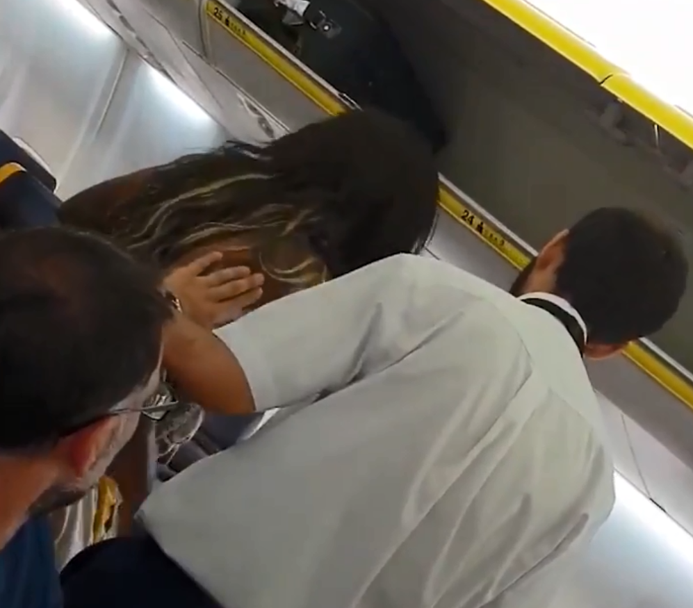  The beginning of the clip shows a steward ushering a woman to sit down after she defends the abused passenger