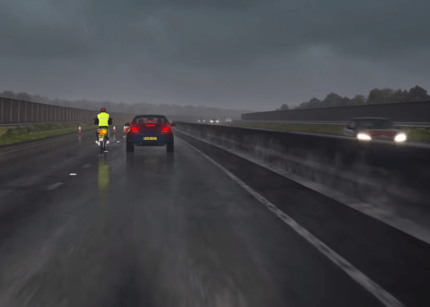 The driving in rain clip features a biker narrowly missing the car in front due to a lane closure