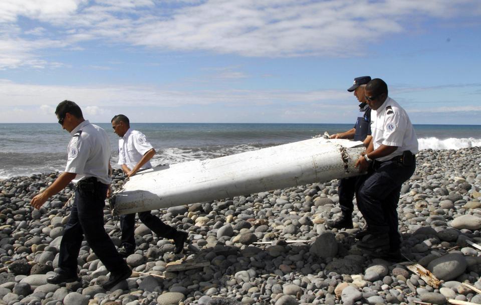  Officers carrying a flaperon from an aircraft apparently washed ashore in Saint-Andre de la Reunion, eastern La Reunion island, France, in 2015