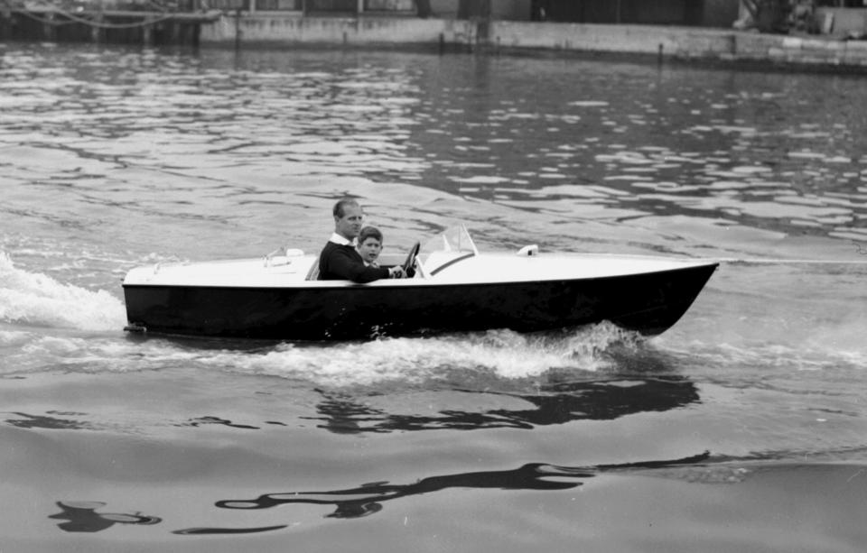  1957: Prince Charles with his father the Duke of Edinburgh at the wheel, as they take a motor boat ride up the River Medina at Cowes