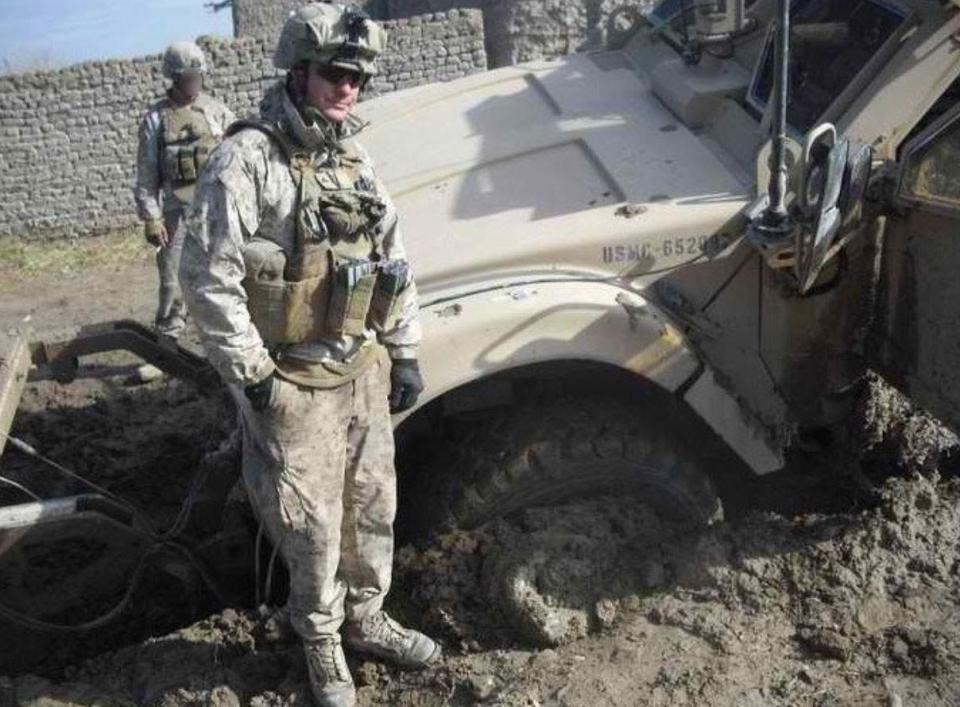 Ian Long stands by a damaged vehicle during a tour during the Afghanistan war